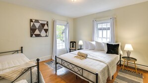 A bedroom with a bed, two bedside tables, a nightstand, a window with curtains, and a wall-mounted light fixture. - Charming Bangor Home w/ Deck < 1 Mi to Downtown (Bangor)