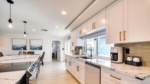 A modern kitchen with white cabinets, a marble countertop, and a coffee bar. - Waterfront Fort Myers Home: Private Pool & Dock (Fort Myers)
