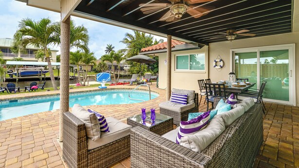 A covered outdoor area with a pool, wicker furniture, and ceiling fans. - Waterfront Fort Myers Home: Private Pool & Dock (Fort Myers)