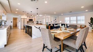 A spacious kitchen with a central island, wooden dining table, and modern appliances. - Waterfront Fort Myers Home: Private Pool & Dock (Fort Myers)