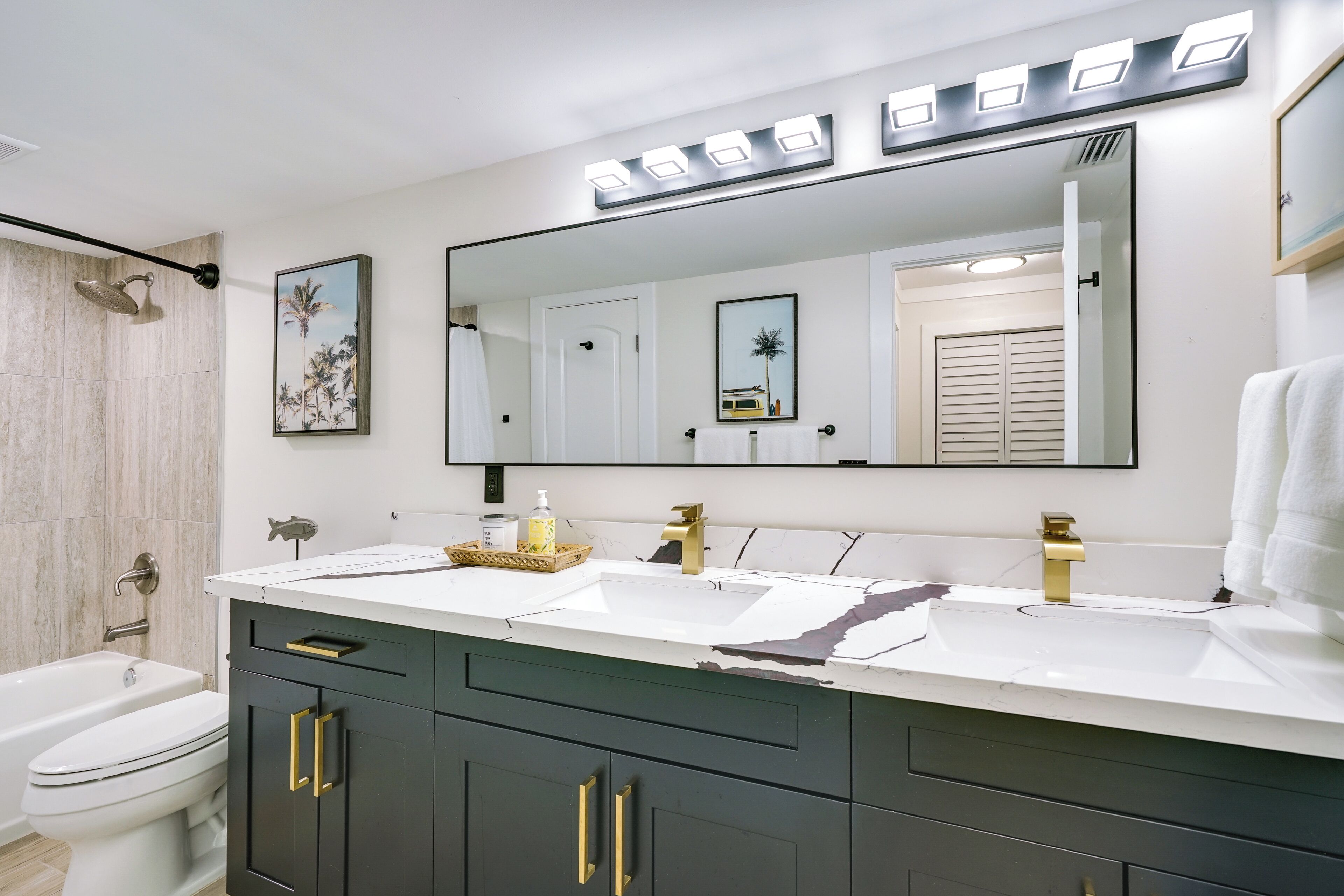 Une salle de bain moderne avec un meuble-lavabo à deux vasques, un grand miroir et un espace douche.