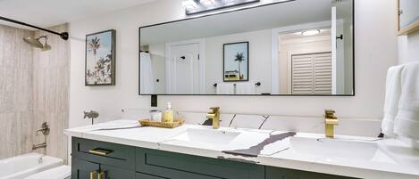 Une salle de bain moderne avec un meuble-lavabo à deux vasques, un grand miroir et un espace douche.