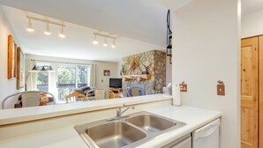 Une cuisine moderne dotée d’un grand évier, d’un lave-vaisselle et d’un mur décoré avec des pierres apparentes.