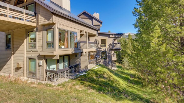 Une maison à plusieurs étages dotée d’un balcon, de grandes fenêtres et offrant une vue sur les arbres et les montagnes.