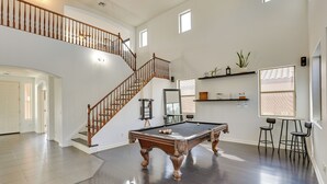 A spacious room with a pool table, a wooden staircase, and a seating area with chairs. - Luxe Family Home w/ Pool, 13 Mi to Dtwn Phoenix! (Laveen)