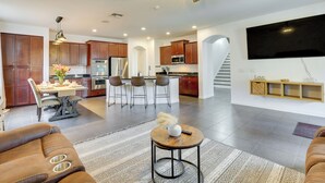 A modern kitchen with wooden cabinets, a dining area with a table and chairs, and a living room with a sofa and a coffee table. - Luxe Family Home w/ Pool, 13 Mi to Dtwn Phoenix! (Laveen)