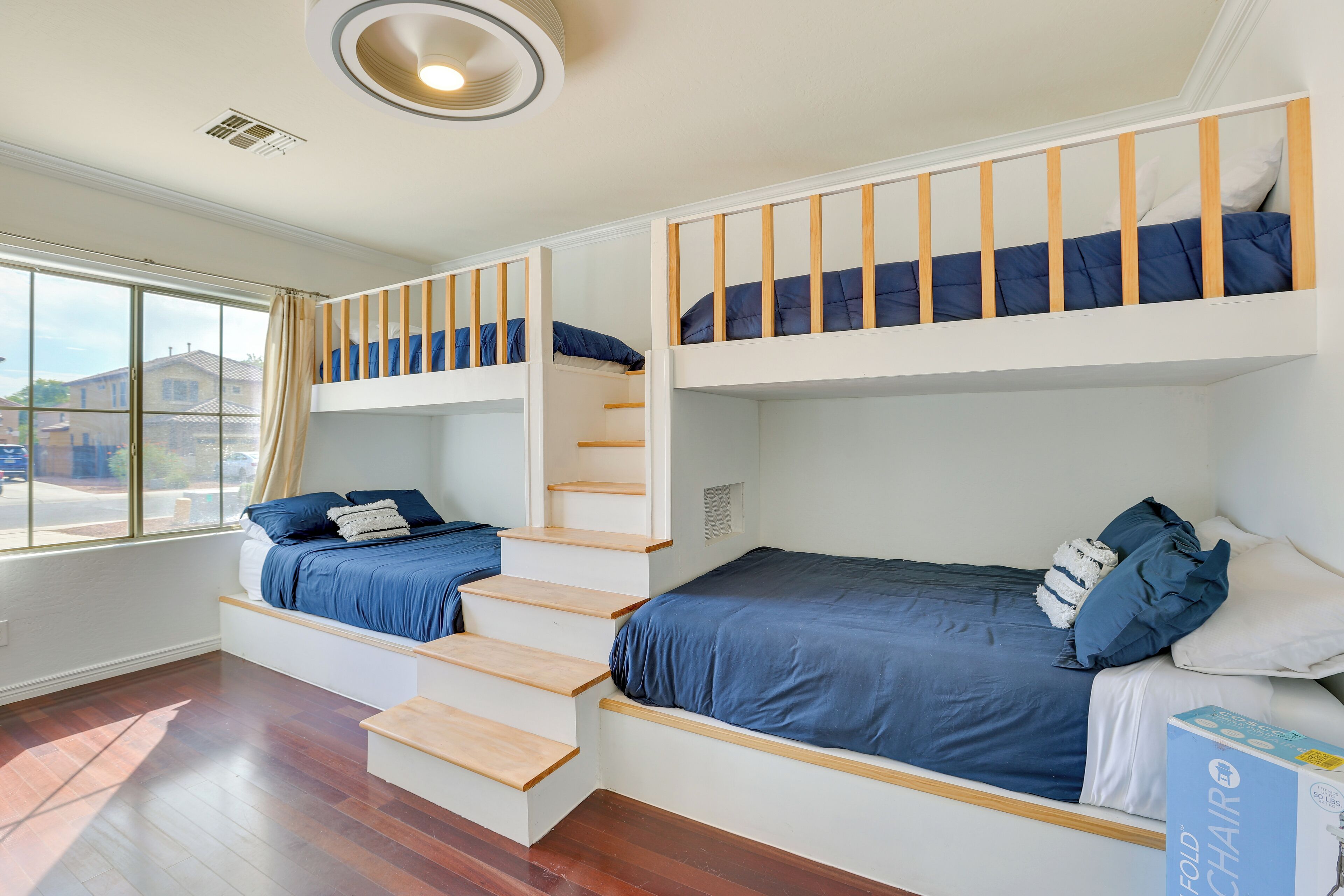 Une chambre avec un lit superposé, une chaise pliante et une fenêtre avec des rideaux.