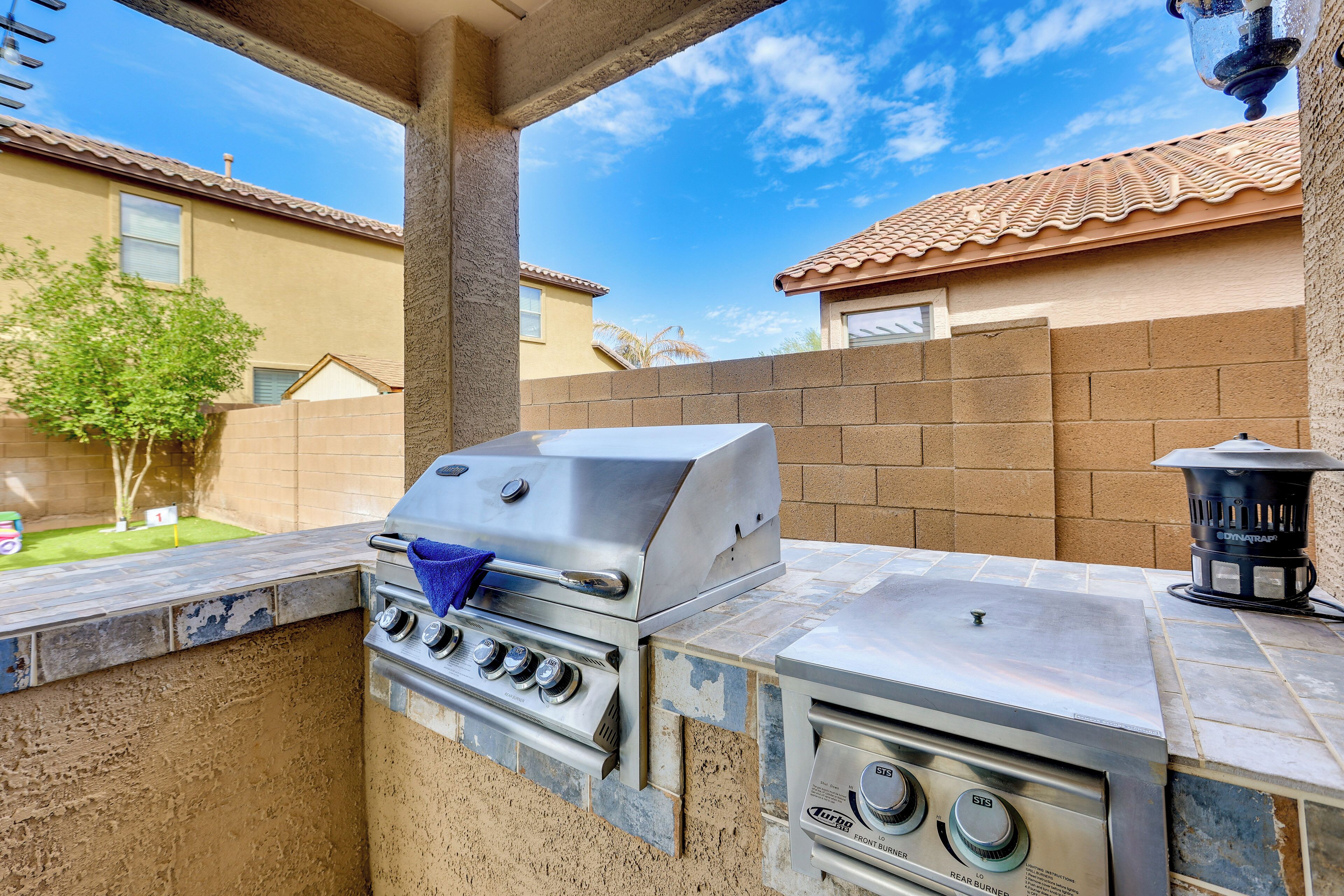An outdoor kitchen with a built-in grill and oven, a stone countertop, and a chimney.