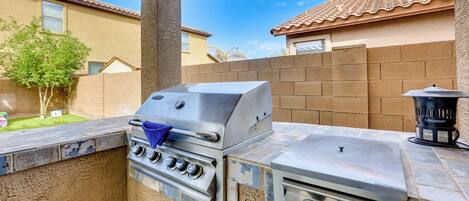 An outdoor kitchen with a built-in grill and oven, a stone countertop, and a chimney.