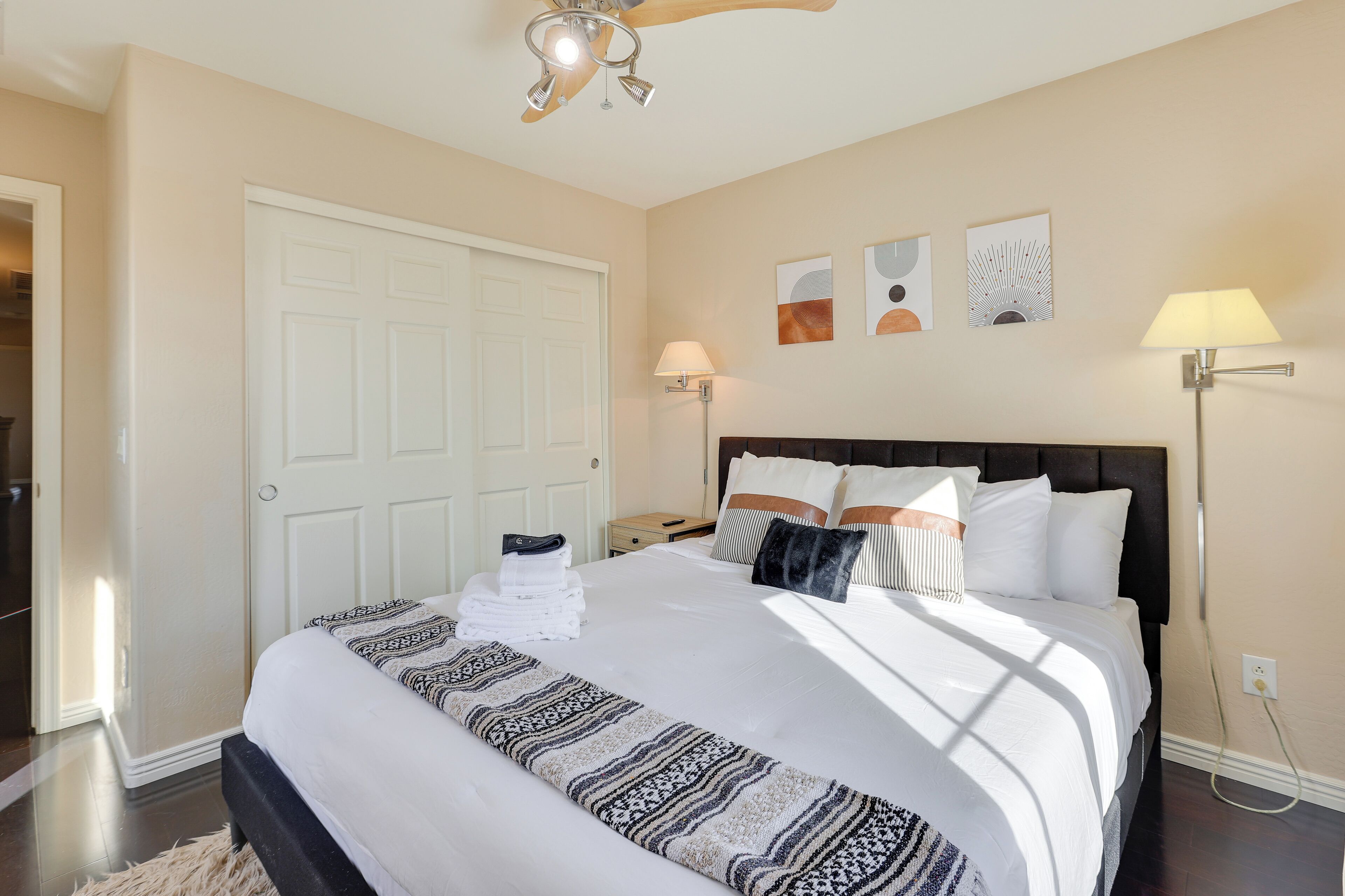 A neatly made bed with a patterned bedspread, a bedside lamp, and a wall clock.
