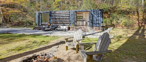 A cabin with a deck, outdoor seating, and a fire pit.
