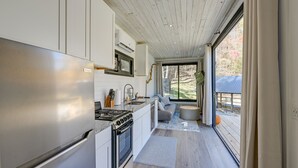 A modern kitchen with stainless steel appliances, a large window, and a view of the outdoors. - Bryson City Tiny Cabin w/ Deck Near River Access! (Bryson City)