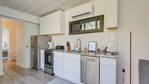 A modern kitchen with white cabinetry, stainless steel appliances, and a granite countertop. - Bryson City Tiny Cabin w/ Deck Near River Access! (Bryson City)