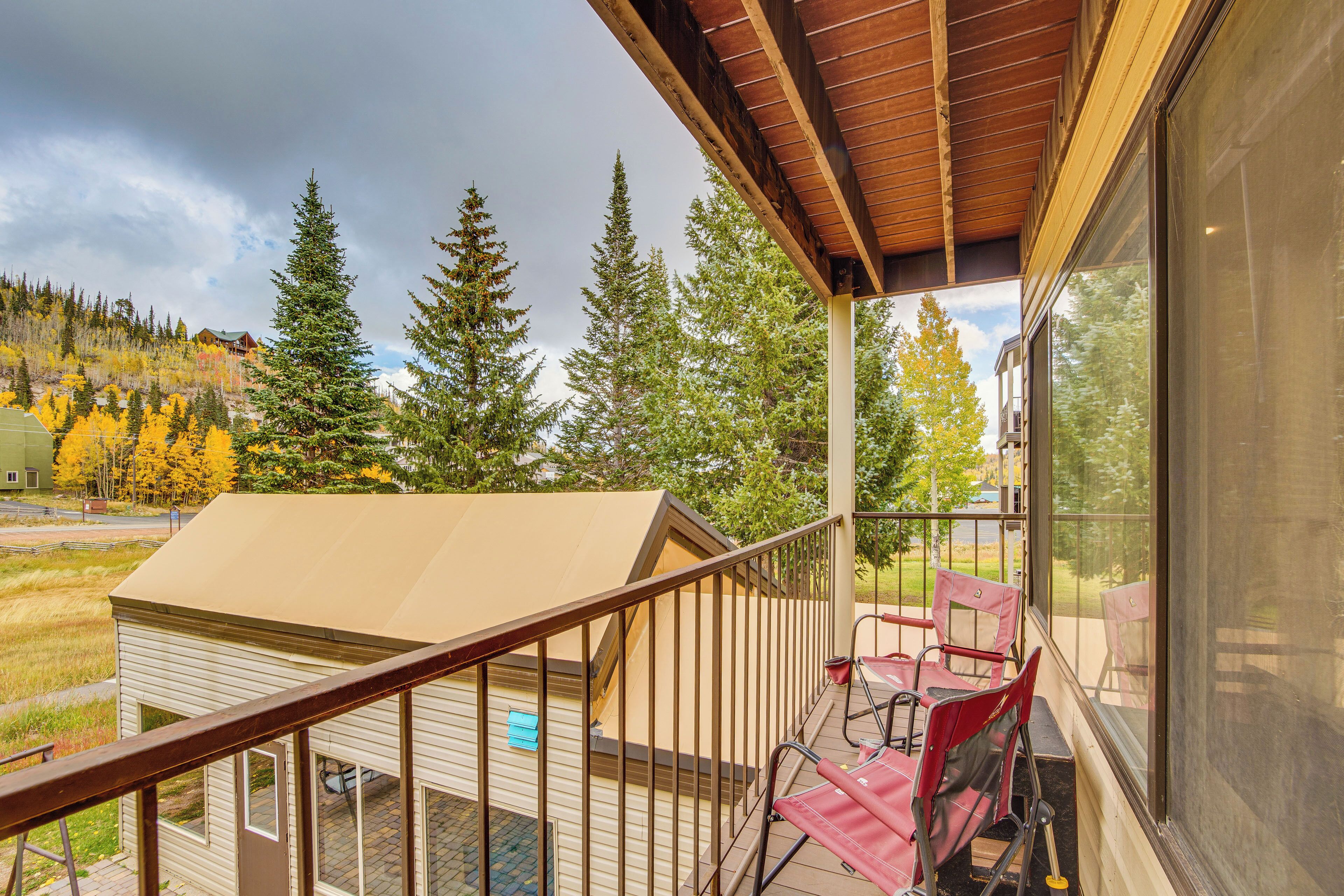 A balcony with a wooden railing, a small table, and chairs.