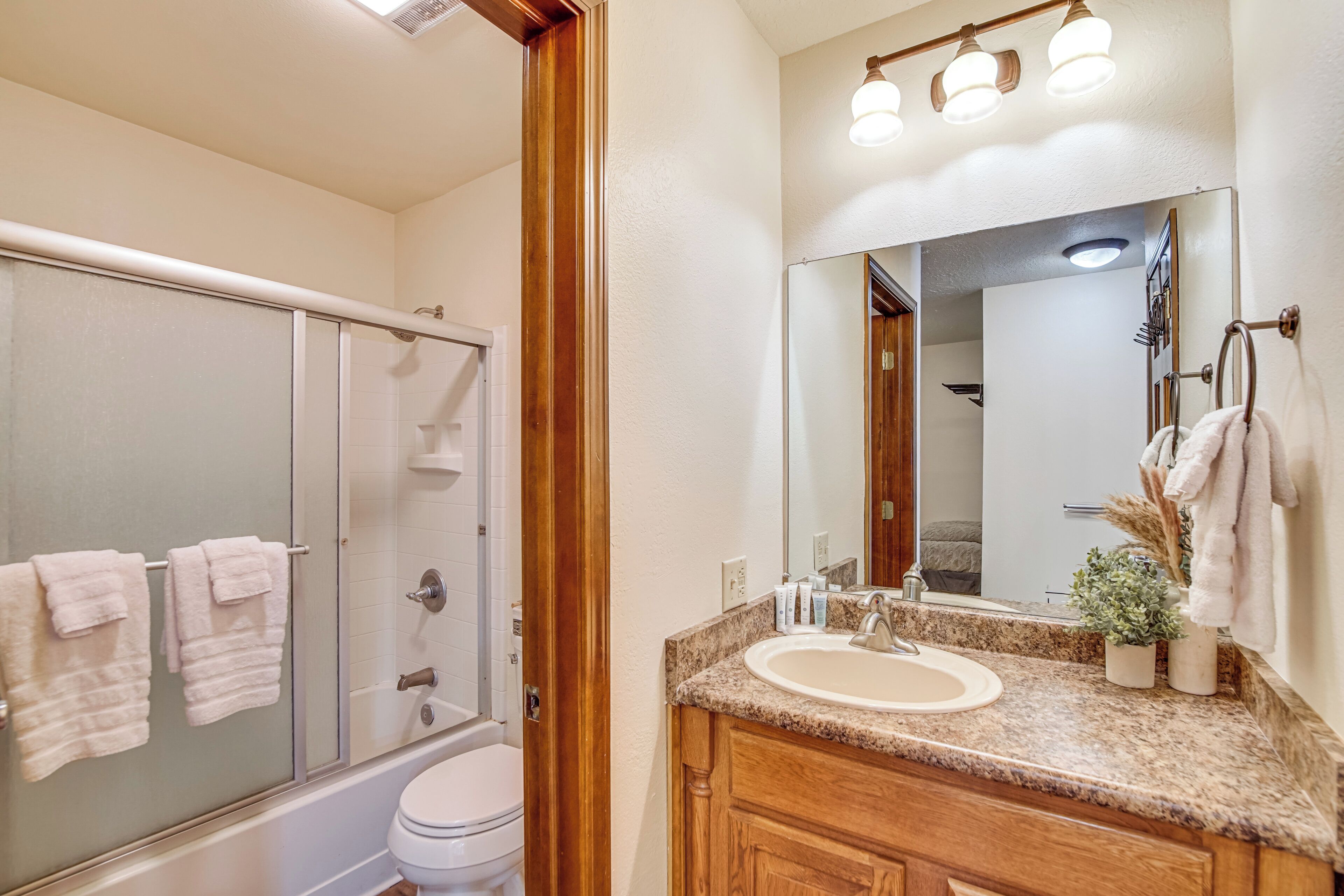 A bathroom with a glass shower enclosure, a toilet, a sink with a vanity, and a mirror above the sink.