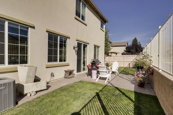 A residential backyard with a patio, outdoor furniture, and a well-maintained lawn.