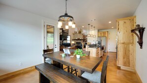 A spacious kitchen with wooden cabinets, a central island, and a dining area with a large wooden table and benches. - Horseshoe Bay Resort Home ~ 6 Mi to Lake Lbj! (Horseshoe Bay)