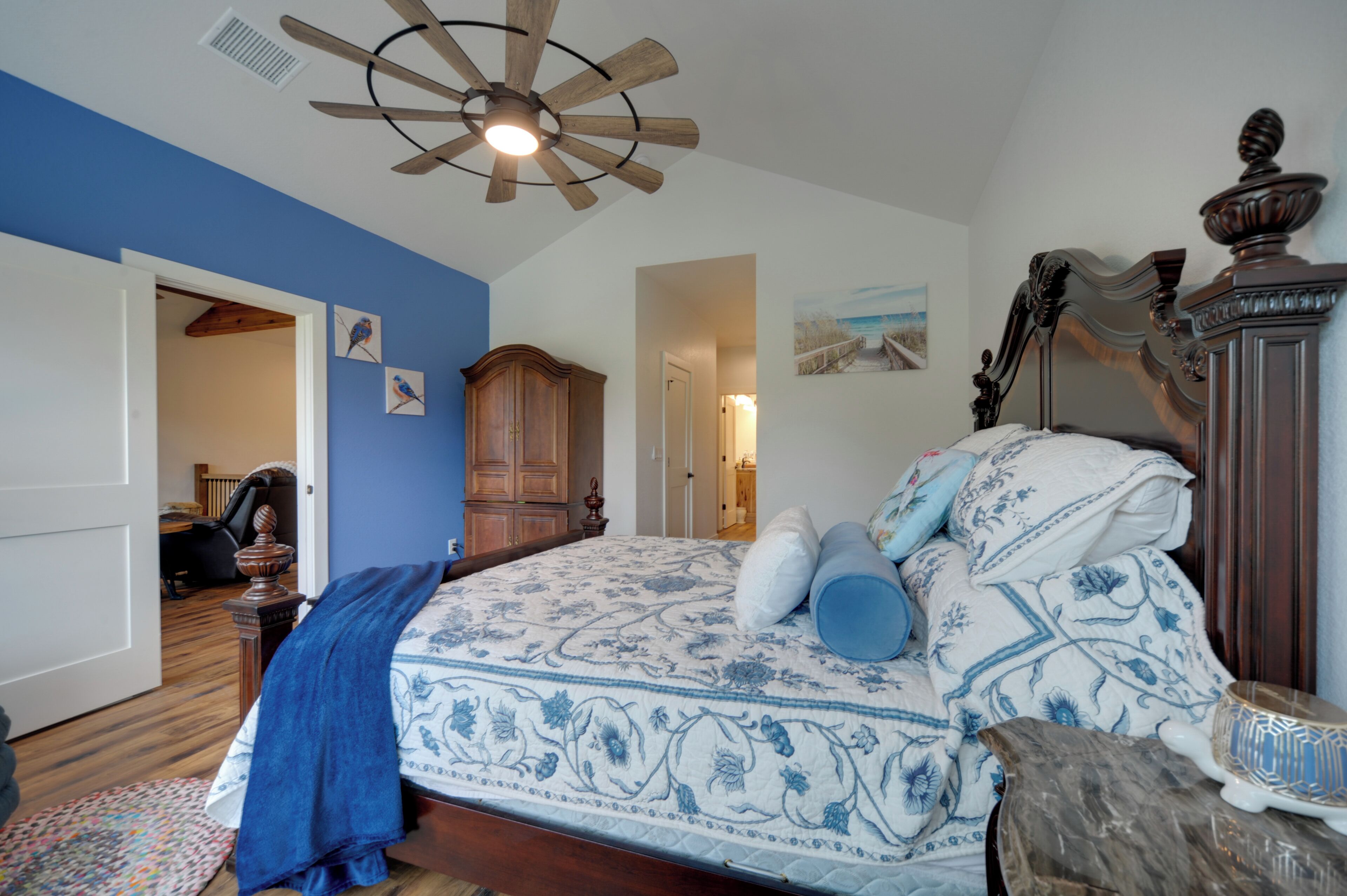 A bedroom with a bed, wooden headboard, and a ceiling fan.