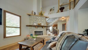 A spacious living room with a stone fireplace, a leather sofa, and a wooden coffee table. - Horseshoe Bay Resort Home ~ 6 Mi to Lake Lbj! (Horseshoe Bay)