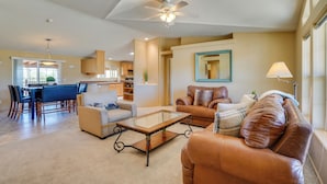 A spacious living room with a glass coffee table, leather sofas, and a dining area with blue chairs. - 11 Mi to Saguaro Nat'l Park! Family Home w/ Deck (Tucson)