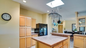 A kitchen with wooden cabinets, a black refrigerator, a built-in oven, and a hanging pot rack. - 11 Mi to Saguaro Nat'l Park! Family Home w/ Deck (Tucson)