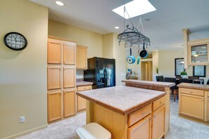 A kitchen with wooden cabinets, a black refrigerator, a built-in oven, and a hanging pot rack. - 11 Mi to Saguaro Nat'l Park! Family Home w/ Deck (Tucson)