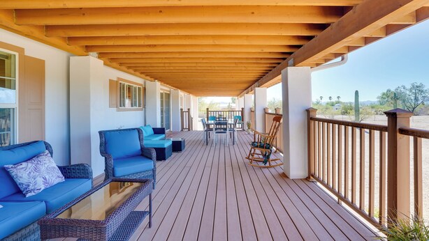 A wooden deck with outdoor furniture, including sofas and a rocking chair, and a view of the desert landscape. - 11 Mi to Saguaro Nat'l Park! Family Home w/ Deck (Tucson)