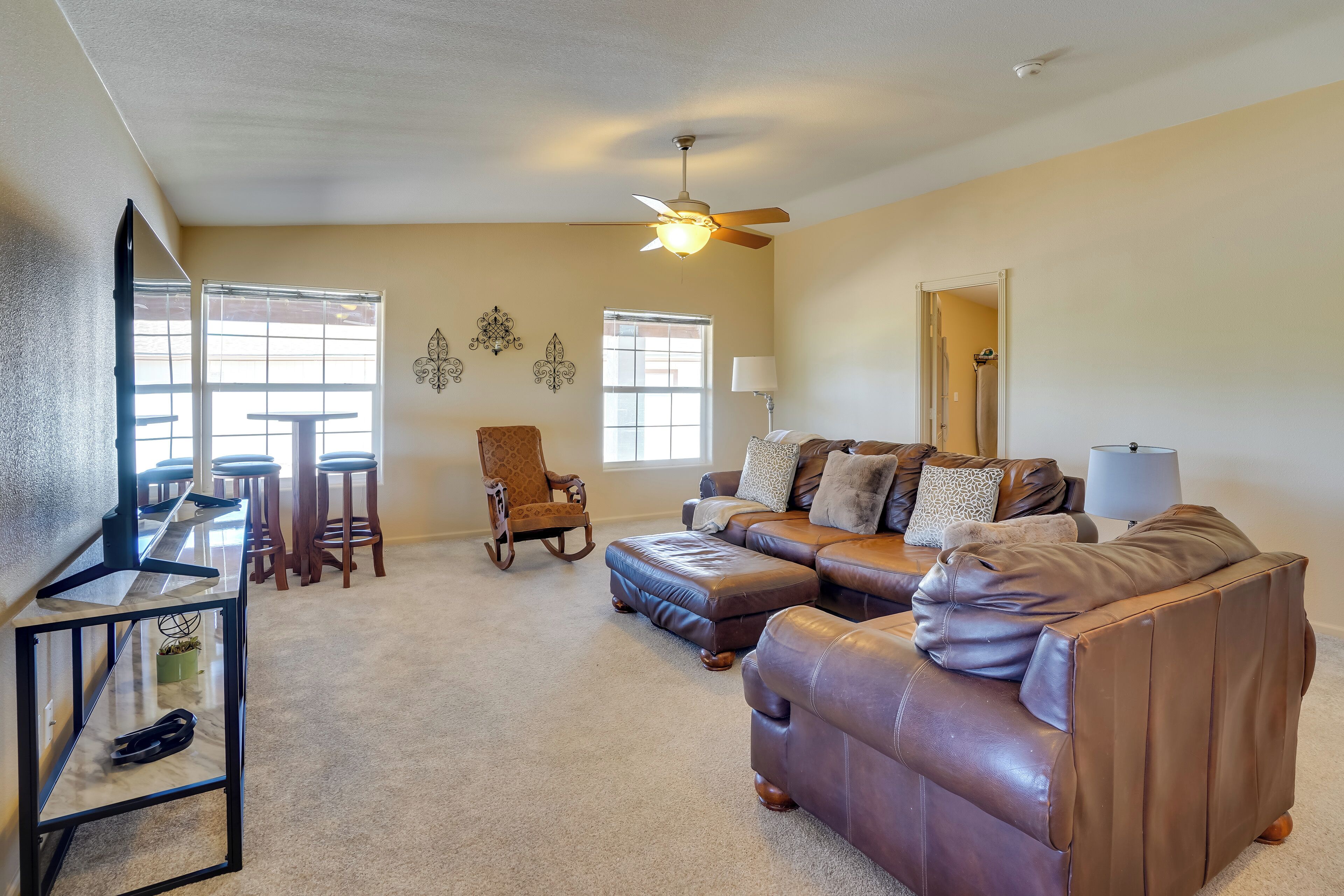 A living room with a sectional sofa, a wooden rocking chair, a glass coffee table, and a ceiling fan.