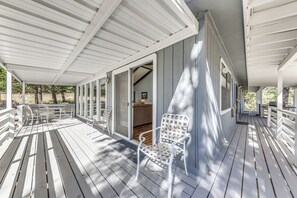 A covered porch with white railings and chairs, leading to a room with a sofa and a table. - Rustic Alto Retreat - Near Hiking, Skiing & More! (Alto)