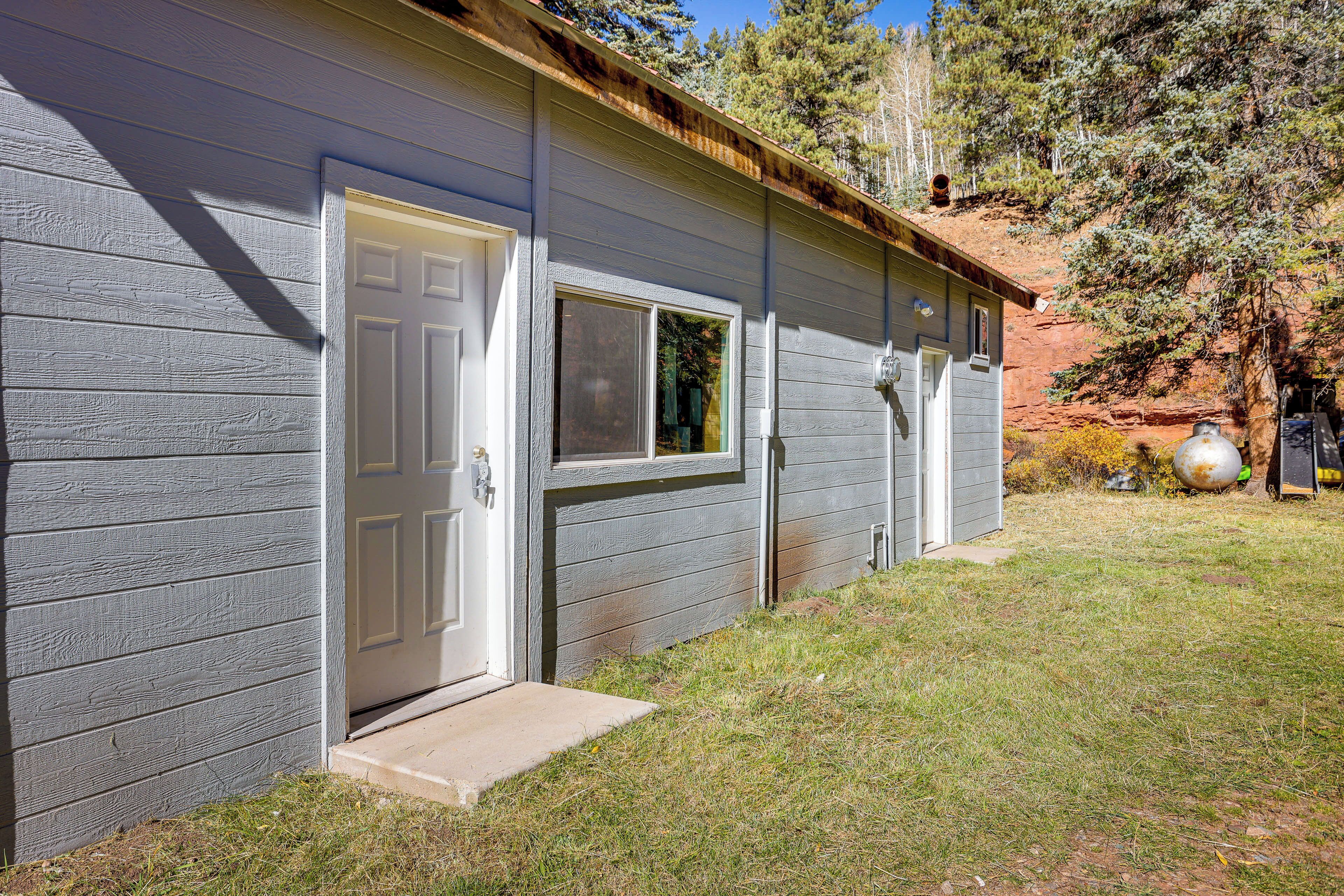 A single-story building with a gray exterior, a white door, and a window.