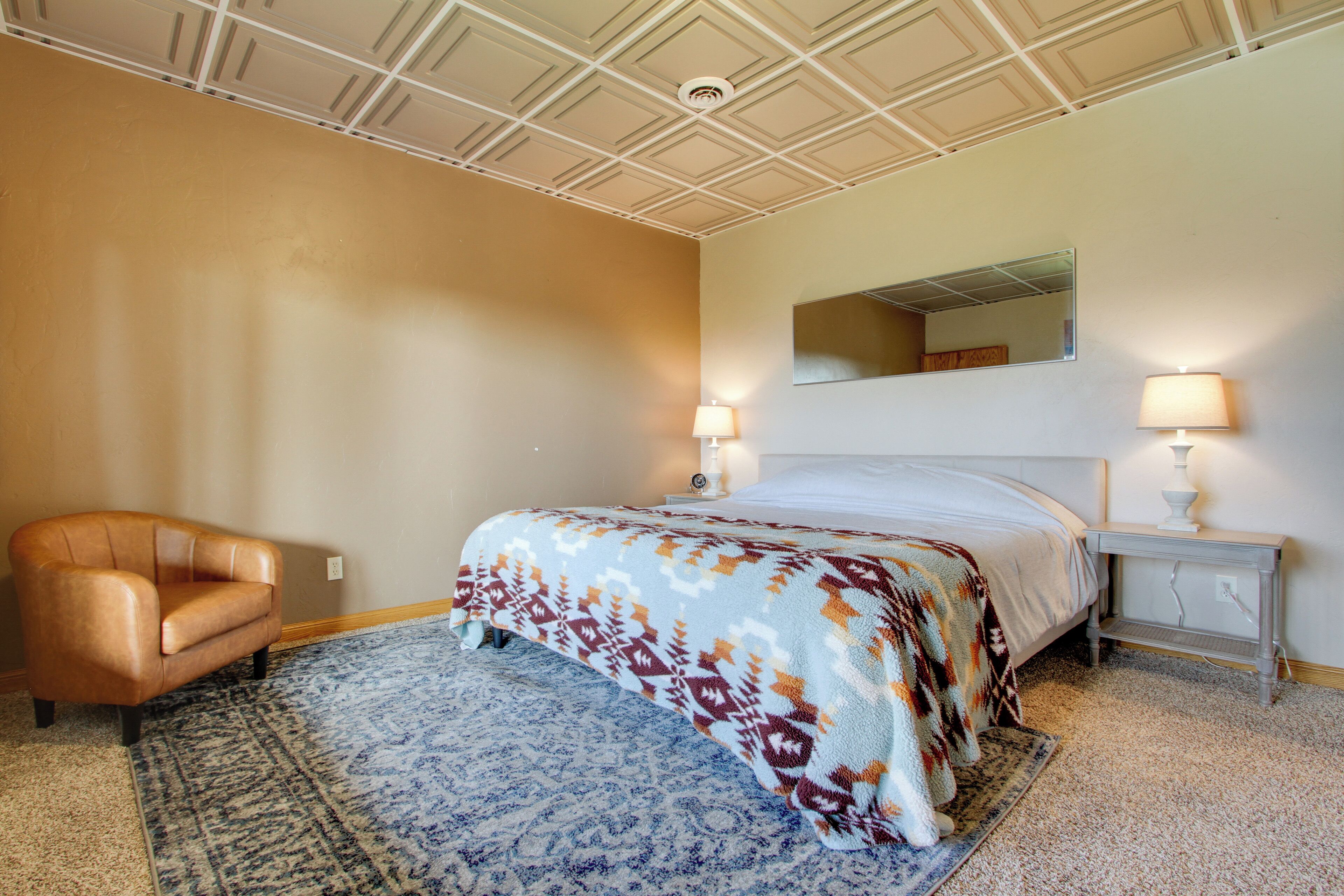 A bedroom with a bed, a chair, a nightstand, and a lamp.