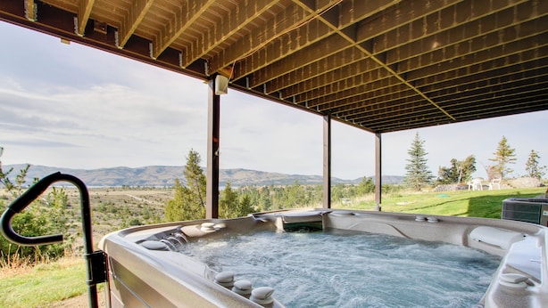 A hot tub under a wooden pergola with a scenic mountain view. - Spacious Canyon Ferry Lake House With Bar & Views! (Helena)