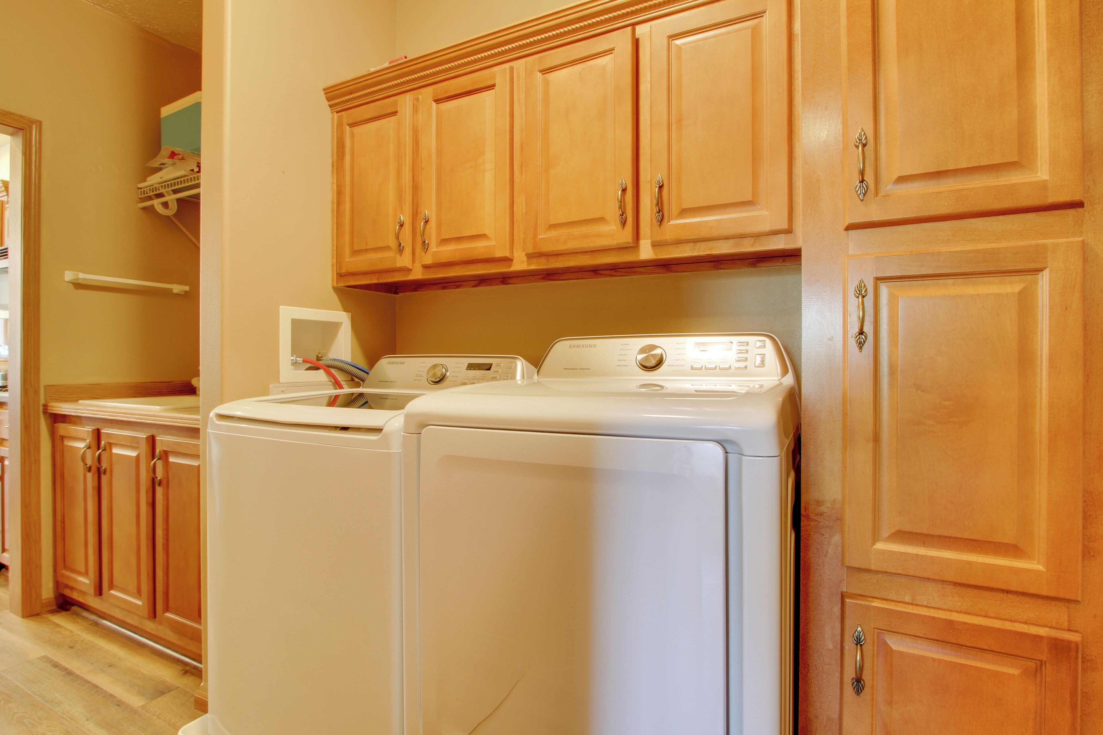 A laundry area with two white washing machines and wooden cabinets.