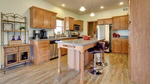 A spacious kitchen with wooden cabinets, a central island, stainless steel appliances, and pendant lighting. - Spacious Canyon Ferry Lake House With Bar & Views! (Helena)