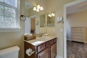 A bathroom with a sink, vanity, and a mirror. There is a window with blinds, a toilet, and a wooden floor. - Desirable Reno Apartment: 15 Mi to Ski Slopes! (Reno)