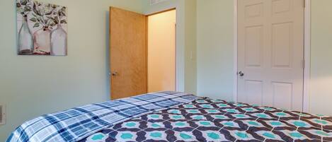 A bedroom with a bed, a door, and a wall-mounted painting.