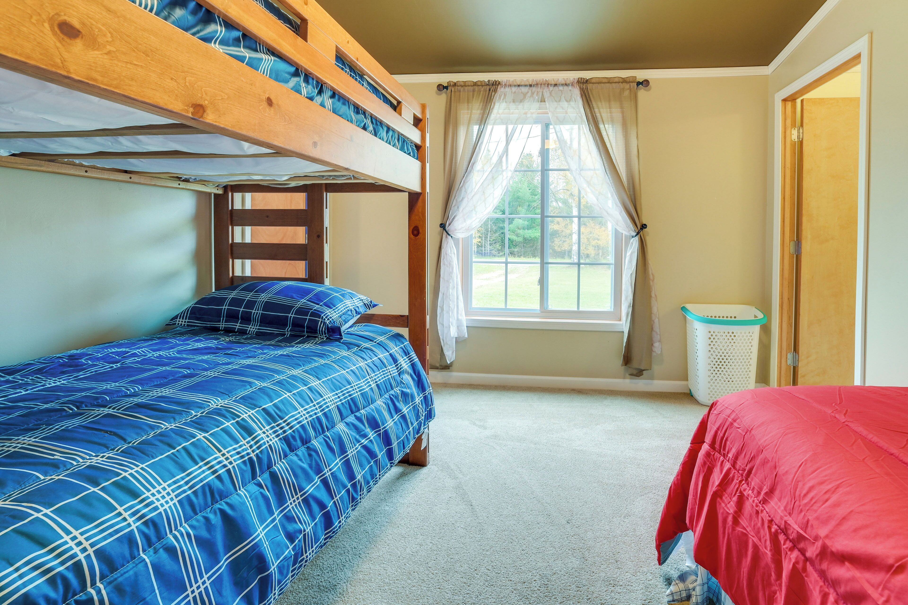 A bunk bed room with a window, a door, and a laundry basket.