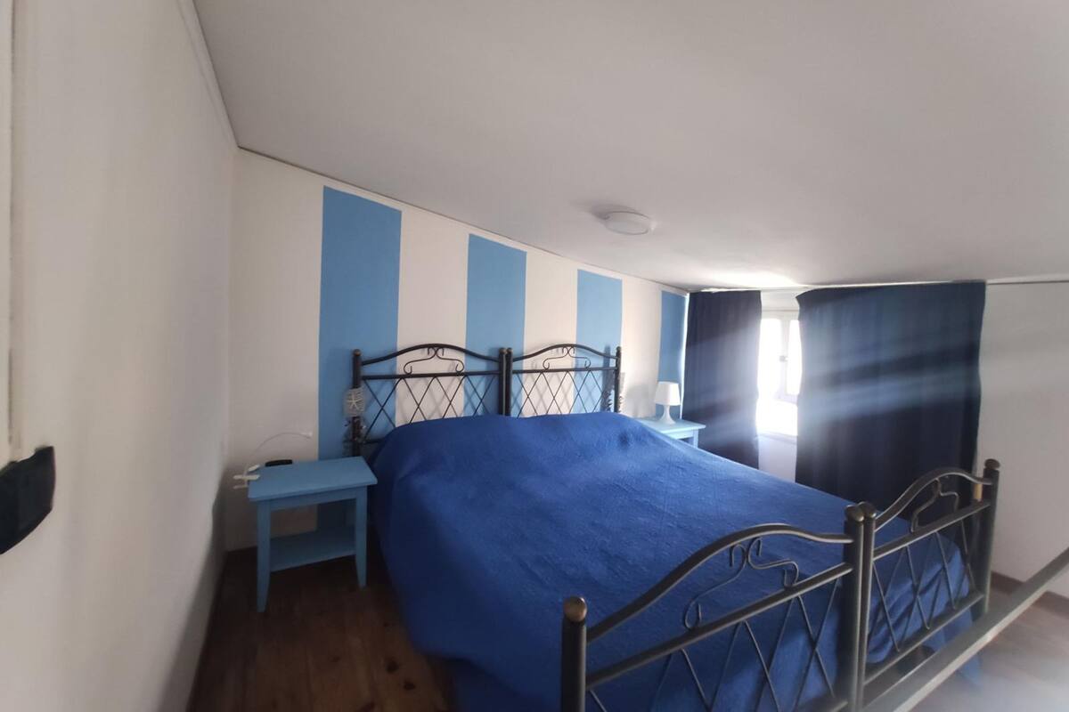 Ein Schlafzimmer mit Bett, Nachttisch und einem Vorhangfenster.