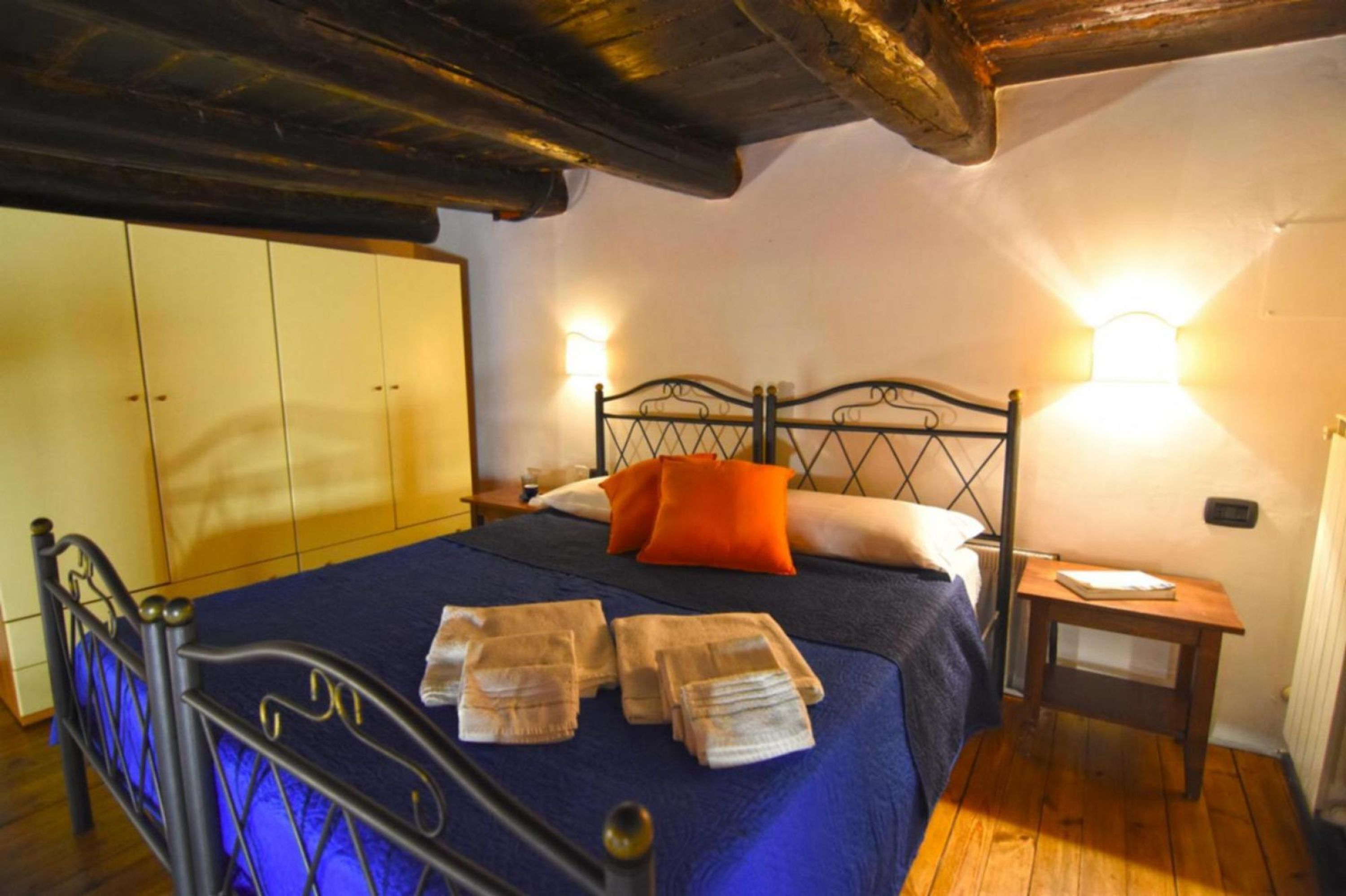 Un dormitorio con cama, armario, mesita de noche y velador.