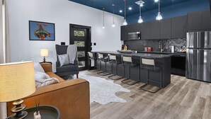 Una cocina moderna con barra, armarios oscuros y ventilador de techo.