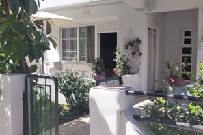 A white house with a balcony, potted plants, and a small garden area. - Annas Downtown Apartment (Chania)