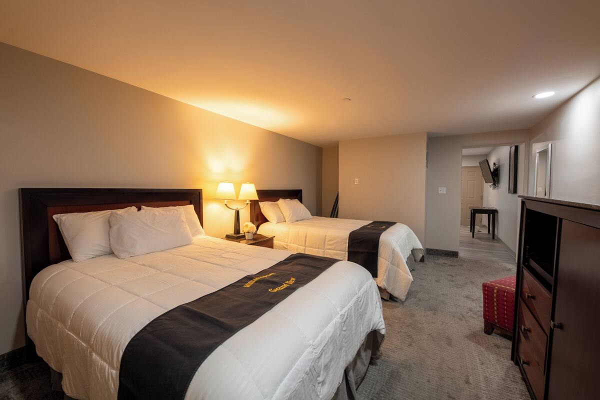 A hotel room with two beds, a desk, and a dresser.