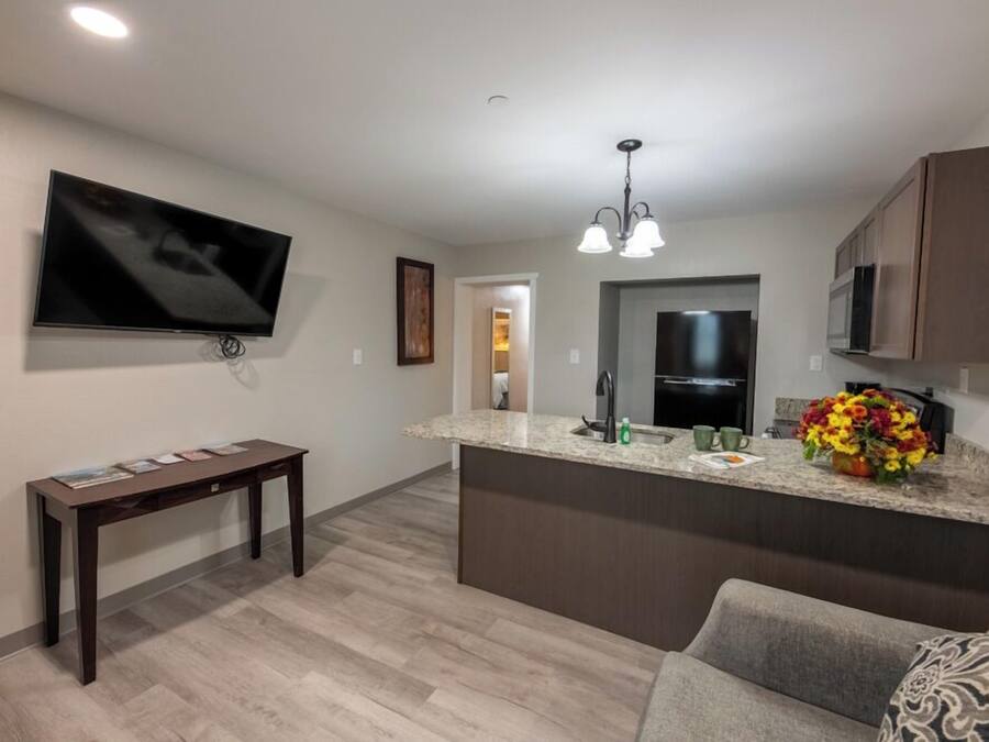 Una cocina moderna con una isla integrada, un televisor de pantalla plana montado en la pared y una zona de comedor con sofá.