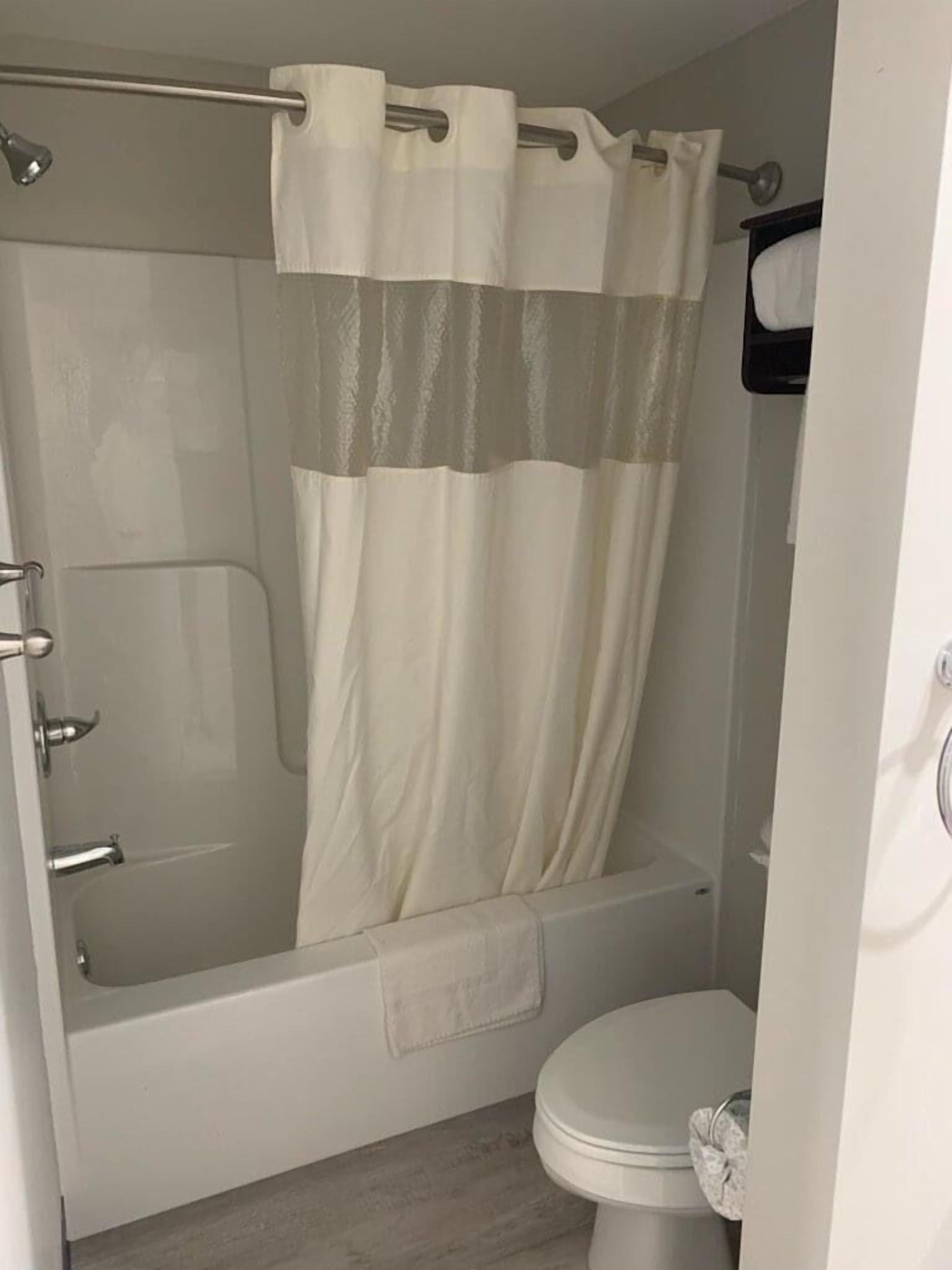 A bathroom with a shower, toilet, and a towel rack.