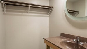 A bathroom with a wooden vanity, a round mirror, and a towel rack. - Lock Haven Grandview Hotel (Mill Hall)