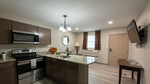 A modern kitchen with a central island, stainless steel appliances, and a pendant light. - Lock Haven Grandview Hotel (Mill Hall)