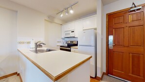 Una cocina compacta con lavamanos, estufa, microondas y refrigerador.