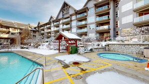 Un hotel con varios balcones, zona de piscina con terraza cubierta y alrededores nevados.
