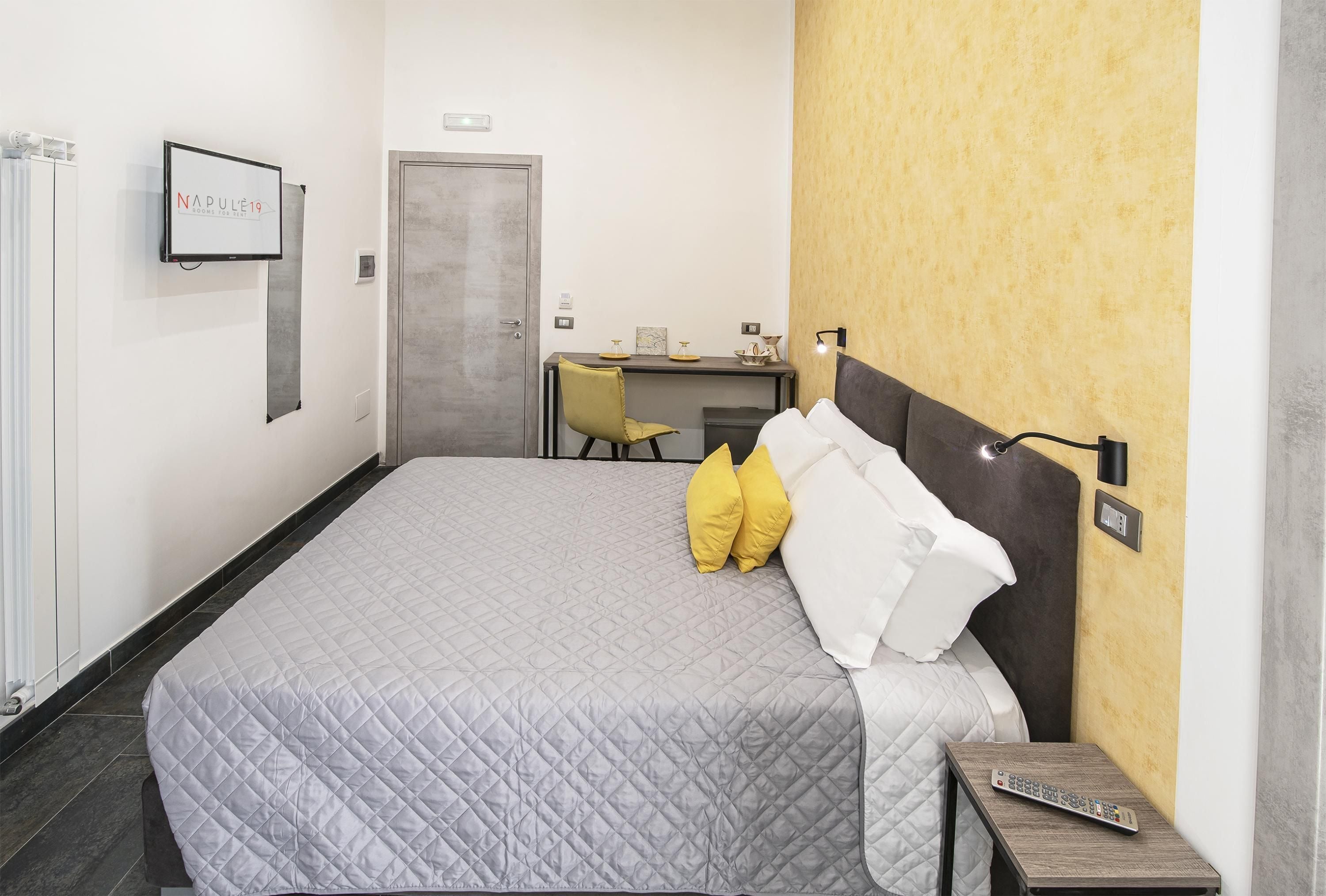 Quarto de hotel com cama, escrivaninha e cadeira.