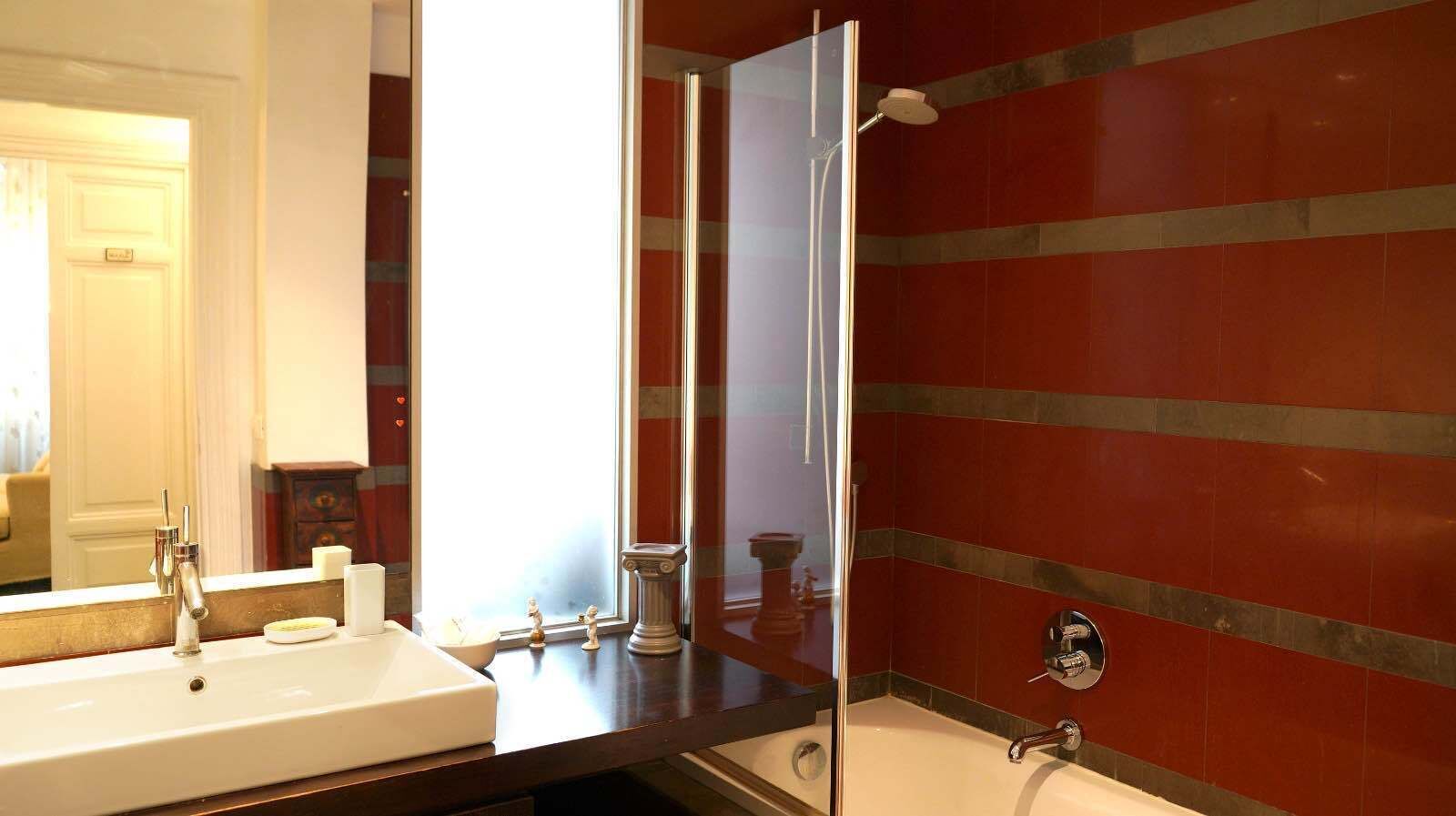 Baño con un espejo grande, un lavabo y una ducha.